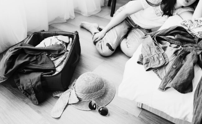 荷造りが終わらず、スーツケースの前で座り込んでいる女性の写真(LCCの7kg制限で苦戦している様子)