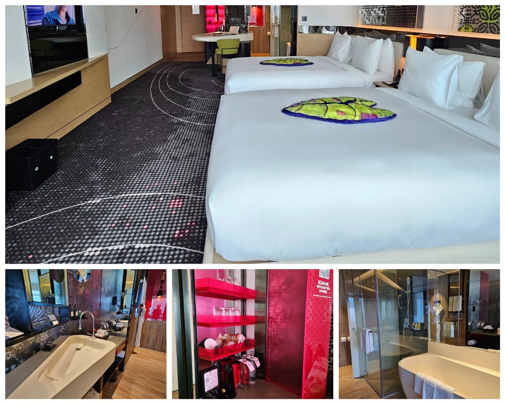 Wクアラルンプールホテルの客室。ツインベッドのある寝室エリア、洗面台やガラス張りのバスルーム、赤を基調としたミニバー設備など、室内の設備とデザインが分かる写真。
